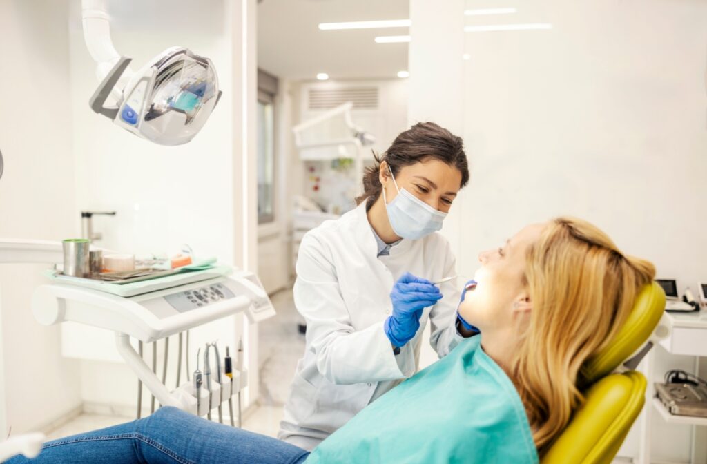 An adult sitting still in a dental chair while they get their teeth examined by a dentist.