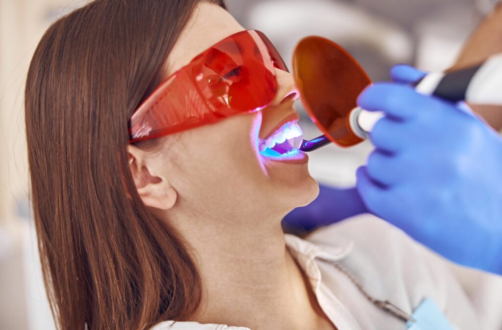 An adult holds their mouth open as they get an in-office teeth whitening treatment done.